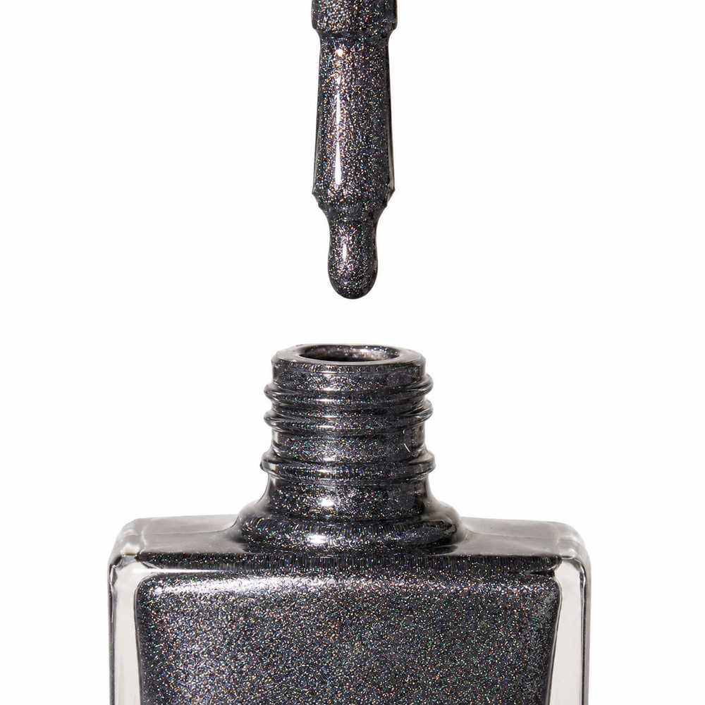 Bottle of Extravaganza dark grey, holographic glitter vegan nail polish by TRUE Nail Polish with dazzling sparkle, glossy gel-effect finish and long-lasting chip-resistant formula.