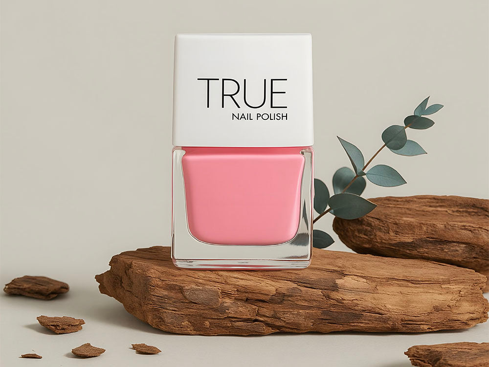 Pink nail polish bottle labeled 'TRUE' on a wooden surface with a natural background